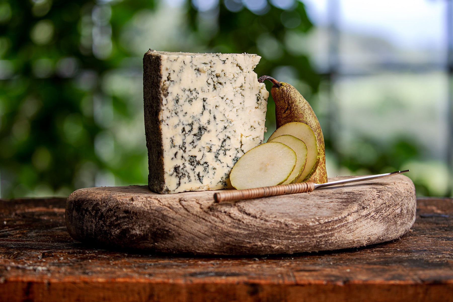 Portion of Hebridean Blue cheese on an old cheese follower with a pear